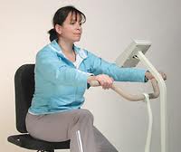 Woman, Ann, using the Theracycle 200, a specialized exercise bike designed for physical therapy and fitness, demonstrating its ease of use and suitability for adults.