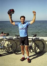Davis Phinney triumphantly standing with a bicycle, representing his achievements and involvement in cycling and Parkinson's advocacy.
