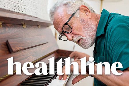 An older man with glasses and a beard playing piano. Text overlays the image stating 'Healthline.'