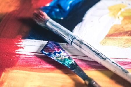 Two paintbrushes on a canvas depicting the therapeutic and creative process of art therapy.